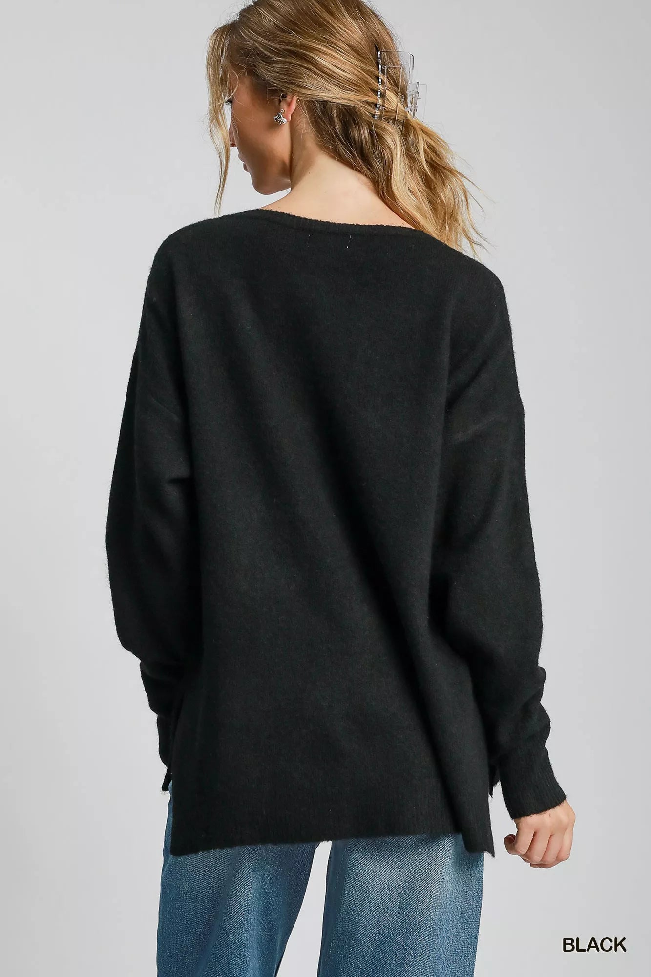 Back view of a woman wearing an Umgee Wool Blended Pullover Sweater in black, showcasing the oversized fit and long sleeves.