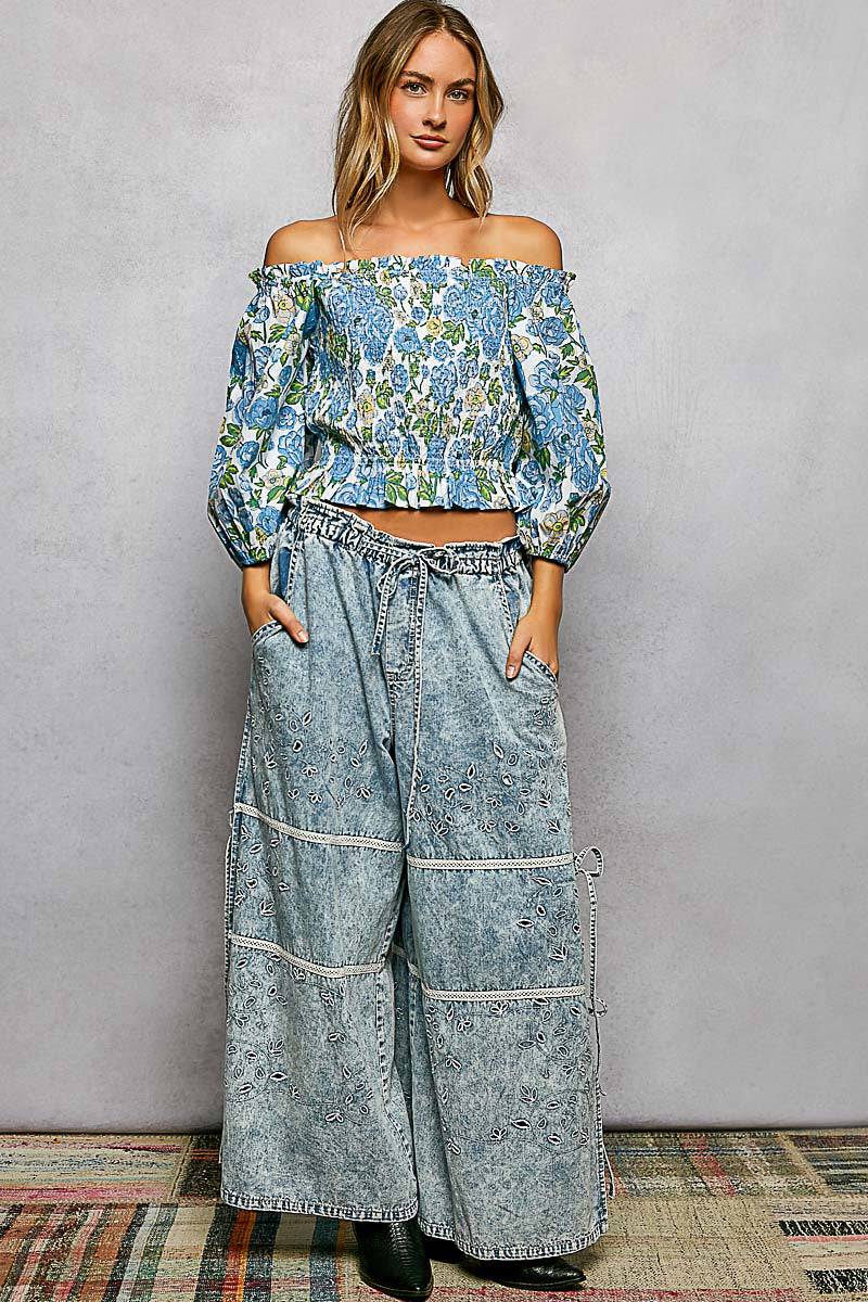 Model wearing POL Floral Print Smocked Off-Shoulder Blouse with wide-leg denim pants.
