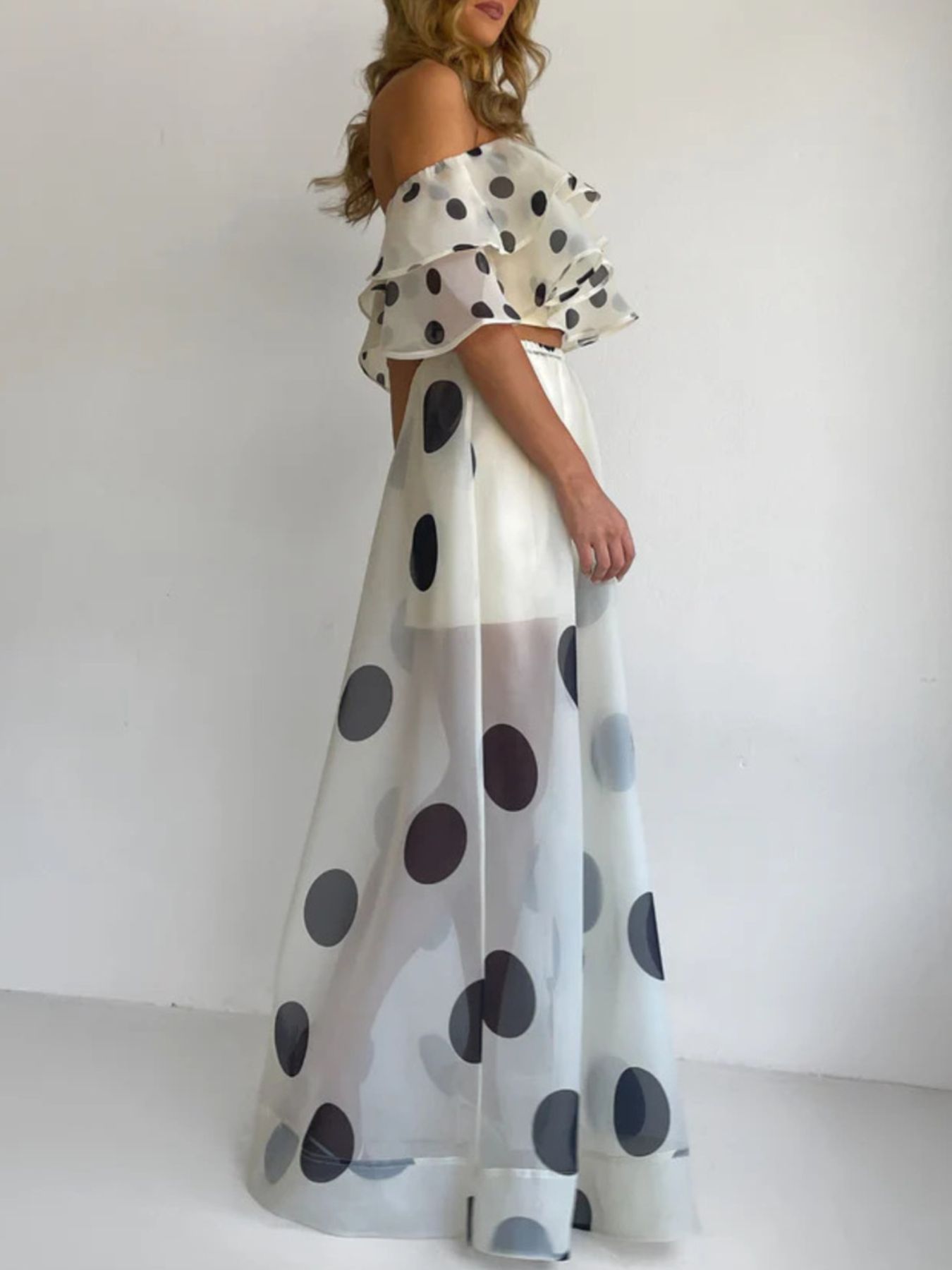 Woman wearing Polka Dot Ruffle Crop Top and Maxi Skirt Set, showcasing an elegant off-shoulder design and bold polka dot pattern.