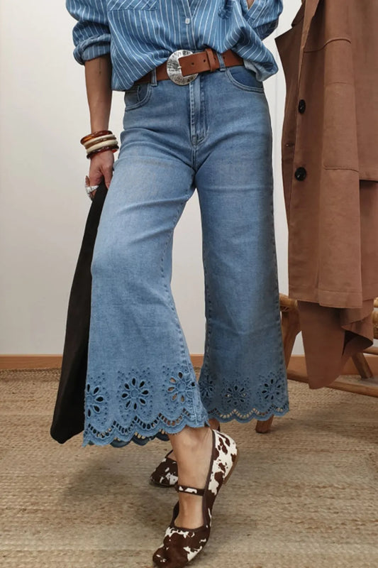 Woman wearing lace detail cropped wide leg jeans with a striped shirt and brown belt, stylishly posed indoors.