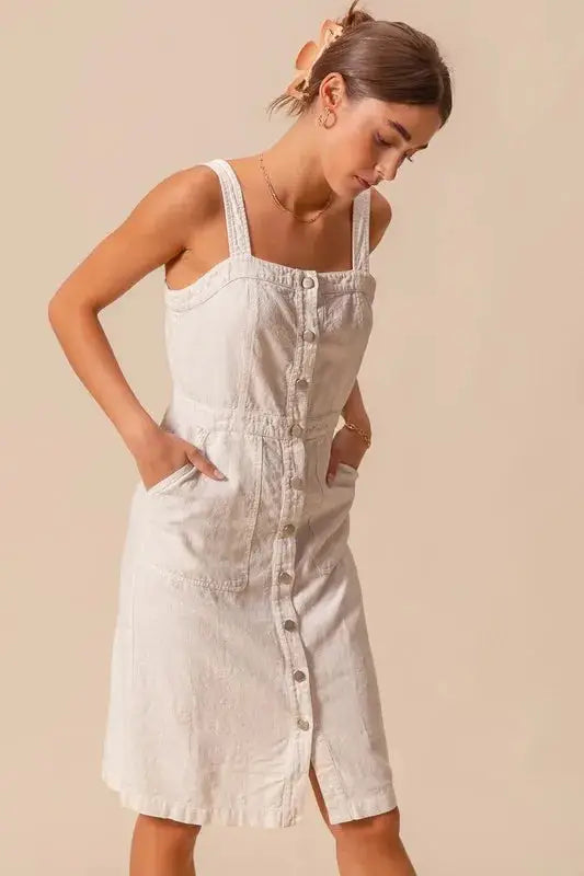 Model styling button down pinafore dress with front pockets and square neckline, perfect for casual layering.