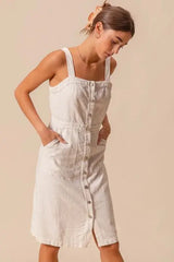 Model styling button down pinafore dress with front pockets and square neckline, perfect for casual layering.