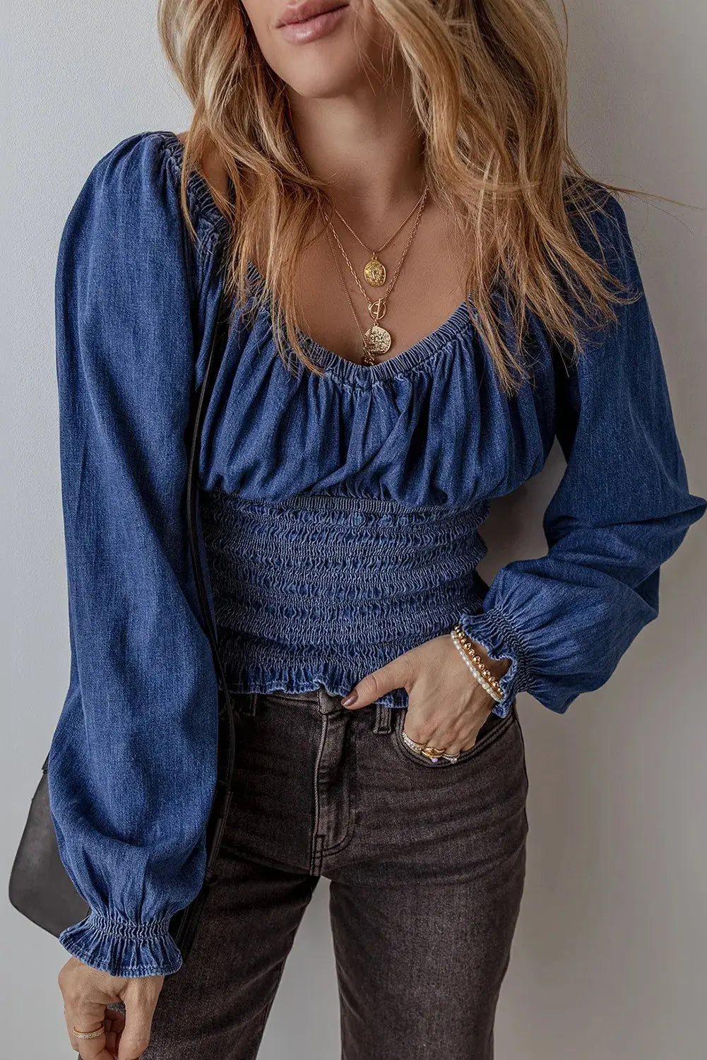 Chic Smocked Long Sleeve Top in Denim with ruched bodice and puff sleeves, styled with dark jeans for a casual yet trendy look.