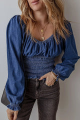 Chic Smocked Long Sleeve Top in Denim with ruched bodice and puff sleeves, styled with dark jeans for a casual yet trendy look.
