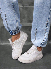 Close-up of ankle cuffs on Studded High Waist Denim Jeans with silver studs and elastic hem, paired with white sneakers for urban style.