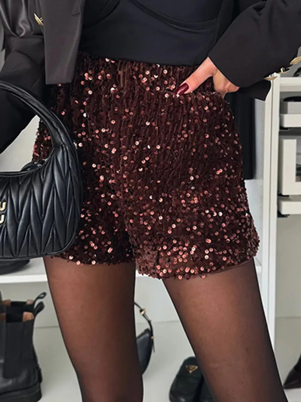 Model wearing Sequin Mid Rise Shorts with a stylish blazer, showcasing a chic party look in a closet setting.