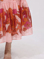 Close-up of blush Button Front Puff Sleeve Dress with bold floral accents and tiered ruffle hem, showcasing elegant design and color.