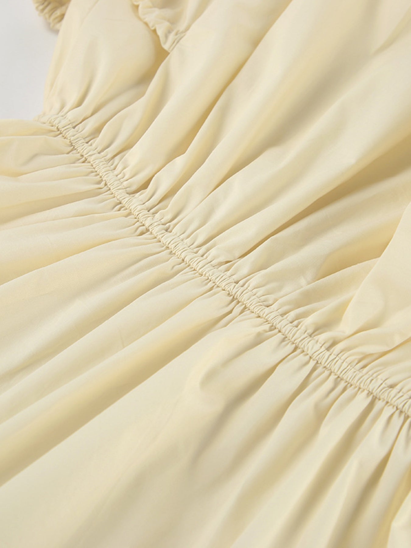 Close-up of elastic waist detail on the Button Front Bubble Hem Dress in soft yellow fabric.