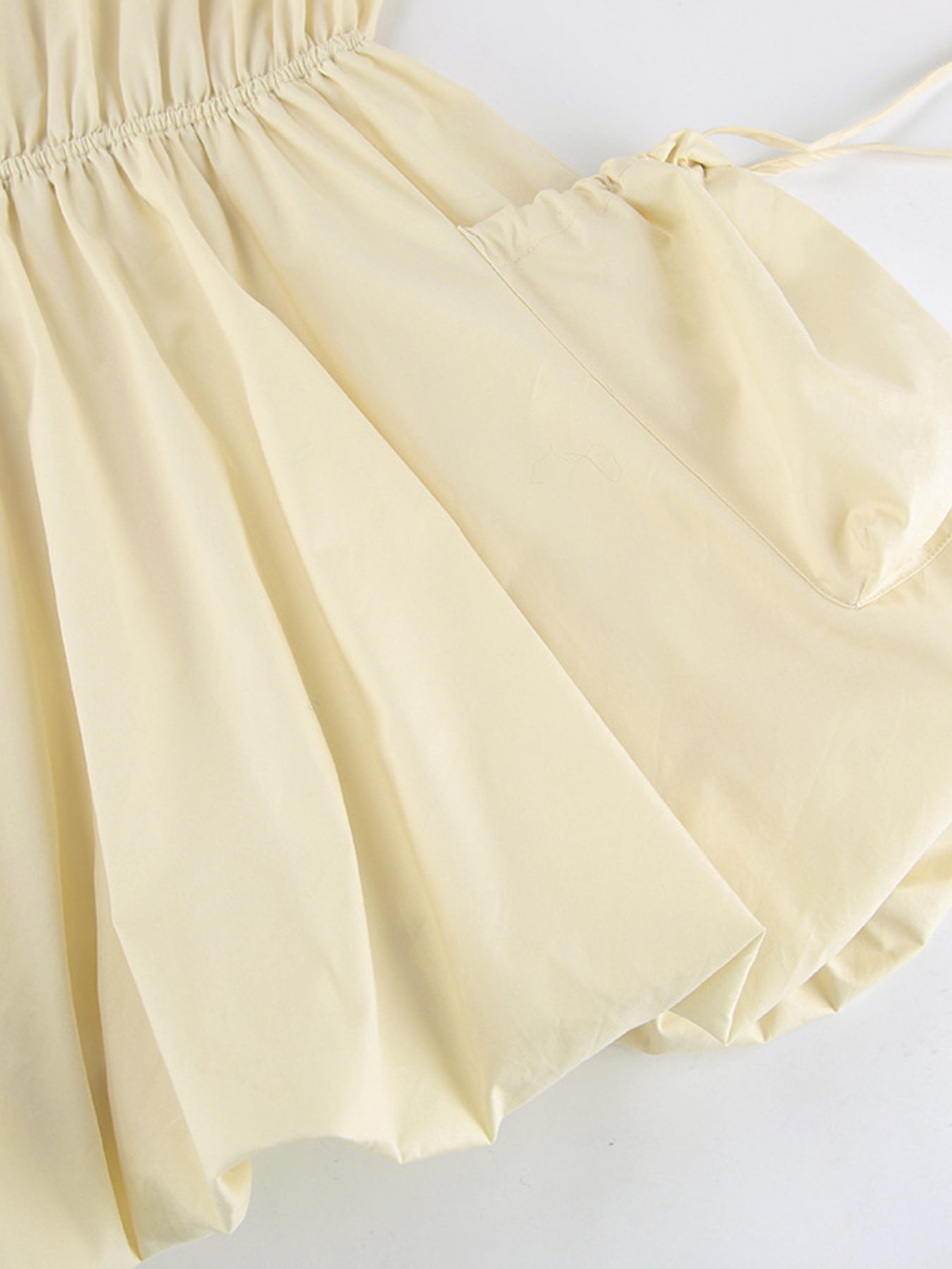 Button Front Bubble Hem Dress with elastic waist and bubble skirt design in light beige fabric.