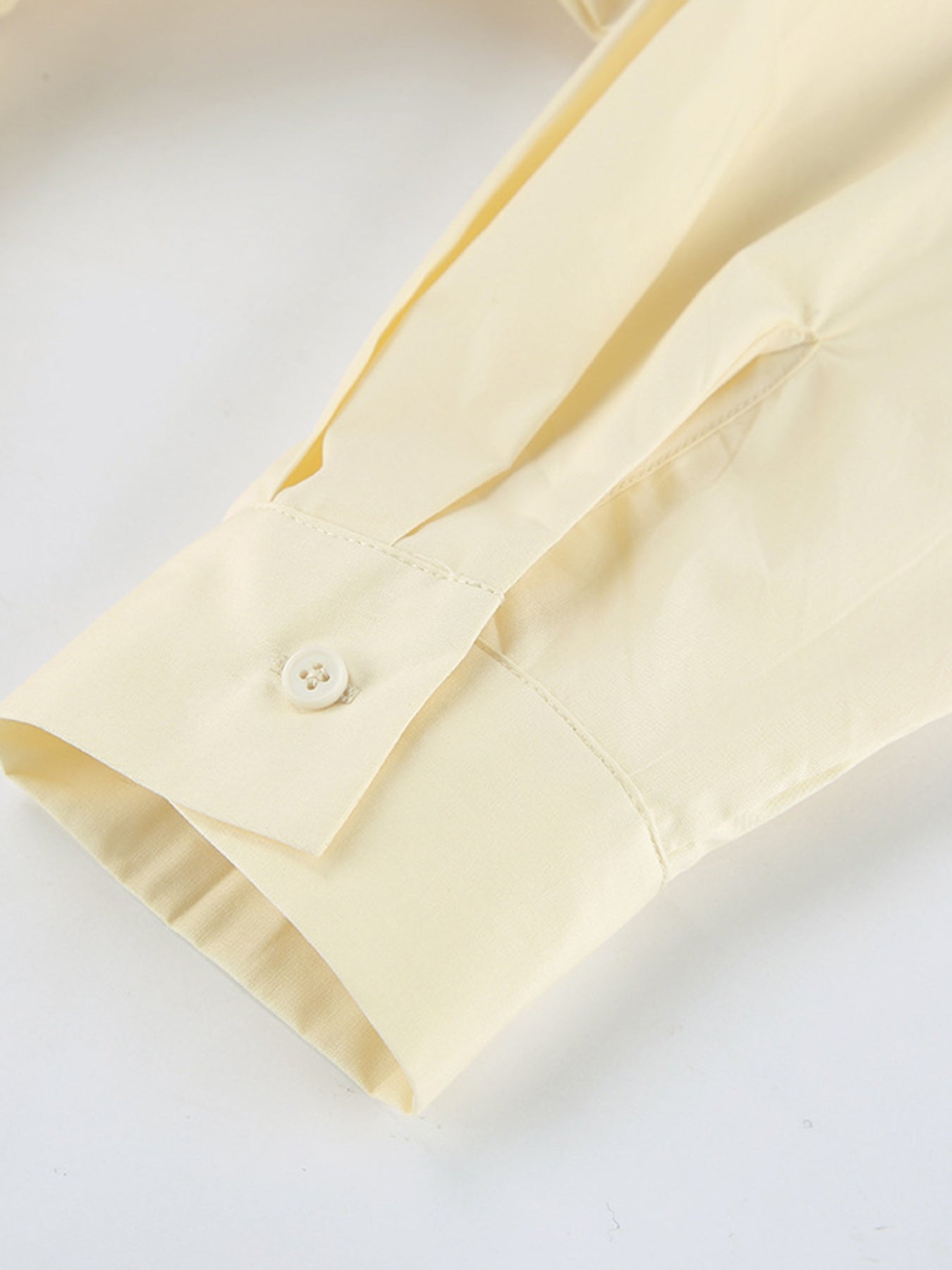 Detail of the button sleeve from the Button Front Bubble Hem Dress in soft yellow fabric.