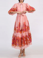 Blush puff sleeve dress with button front, floral accents, belted waist, and tiered ruffle hem.