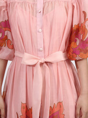 Close-up of button front puff sleeve dress in blush with floral accents, featuring a belted waist and tiered ruffle hem.