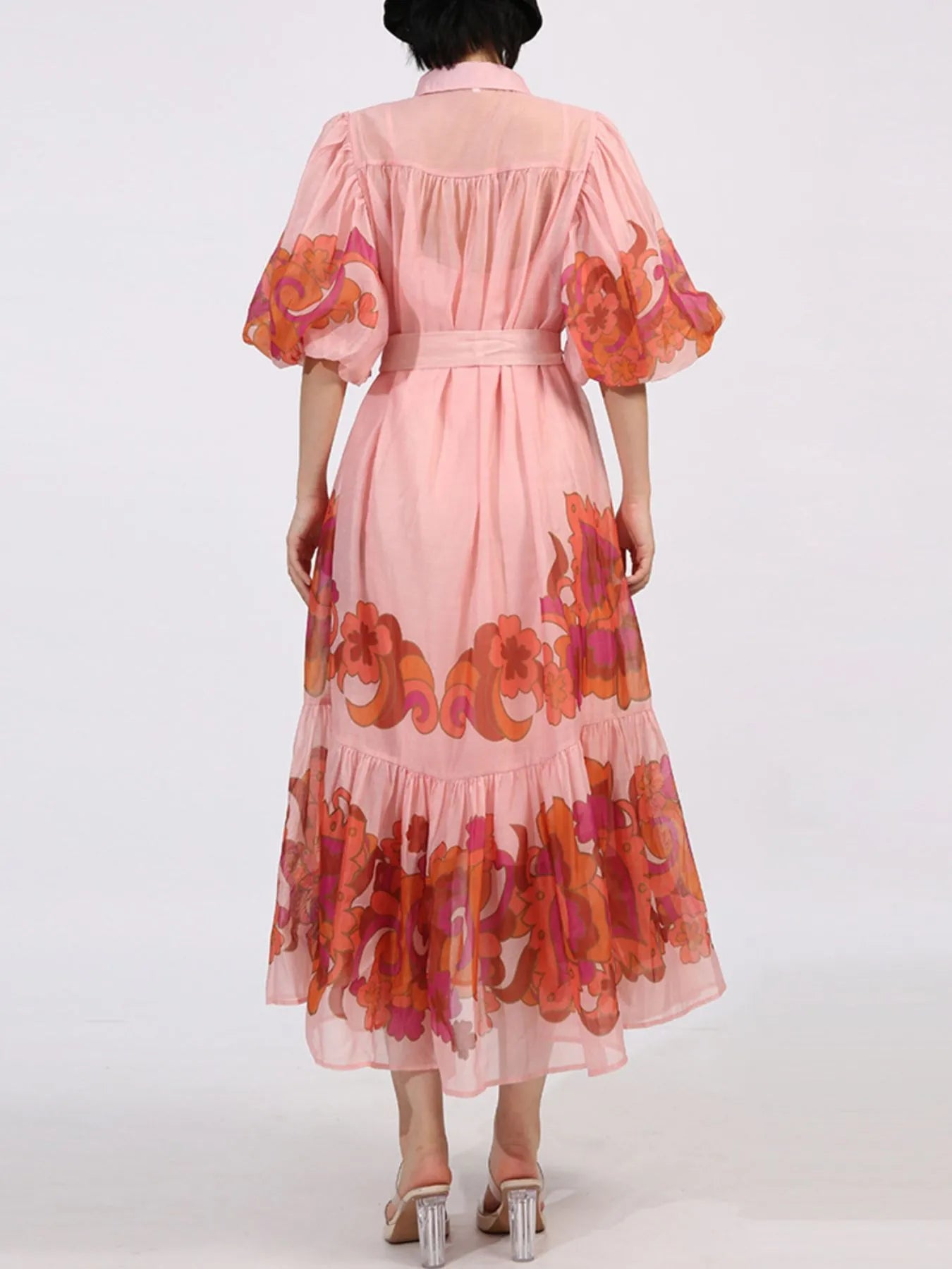 Back view of Button Front Puff Sleeve Dress in blush with floral pattern, tiered ruffle hem, and belted waist, showcasing elegant design.