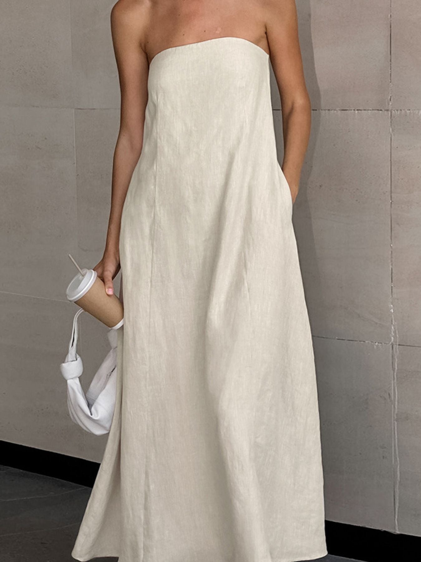 Smocked Back Tube Dress worn by a model, showcasing a strapless maxi design in a light color with pockets.