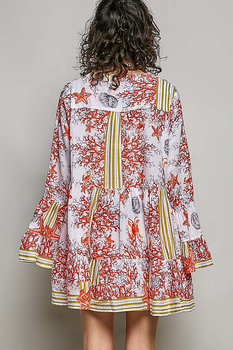 Back view of a woman wearing POL Striped Floral Long Sleeve Mini Dress with Pintuck Detail featuring coral and starfish print.