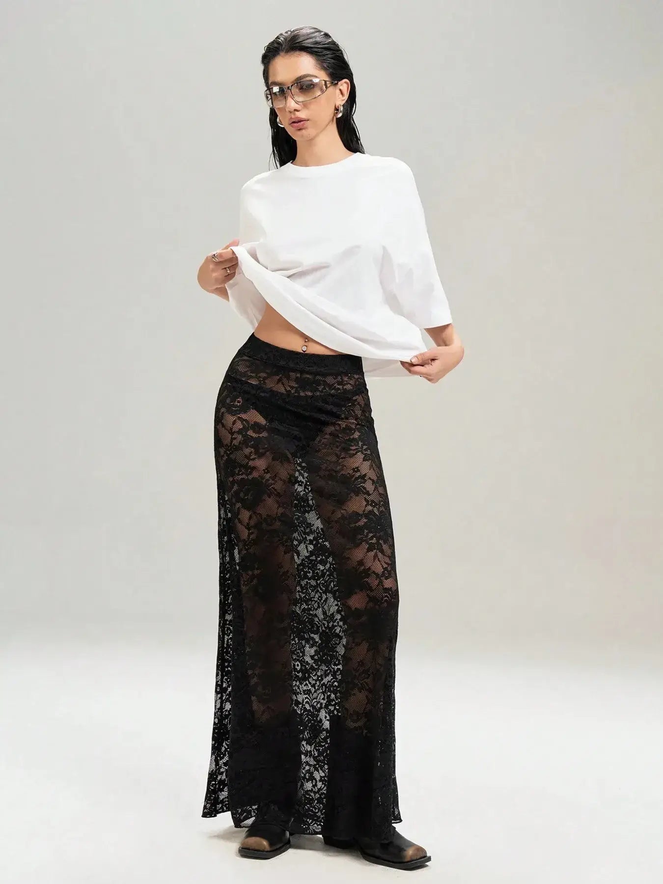 Chic black lace maxi skirt worn with a white top, blending elegance with an edgy twist, perfect for layering over various outfits.