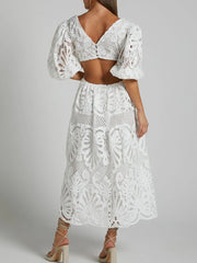 Back view of a white lace crochet V-neck dress with cutout back, showcasing intricate detailing and bold modern design.