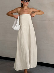 Model wearing a Smocked Back Tube Dress in cream color, paired with a white bag and sunglasses.