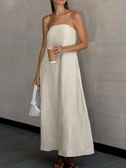 Model wearing a Smocked Back Tube Dress in a light color, holding a coffee cup and standing against a neutral background.