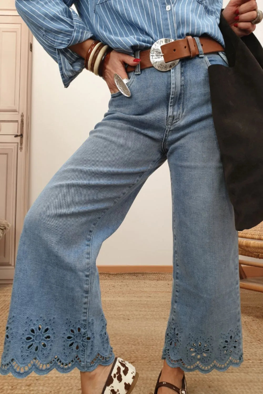 Cropped wide leg jeans with lace detail, styled with a blue striped shirt and accessories, showcasing a trendy outfit.