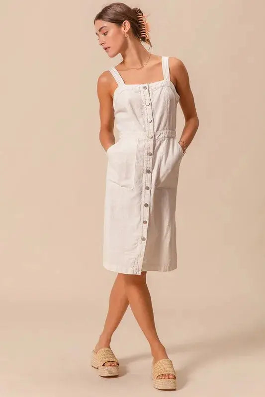 Pinafore dress with pockets in a button down style, featuring wide straps and a relaxed fit for versatile styling.