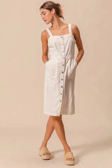 Pinafore dress with pockets in a button down style, featuring wide straps and a relaxed fit for versatile styling.