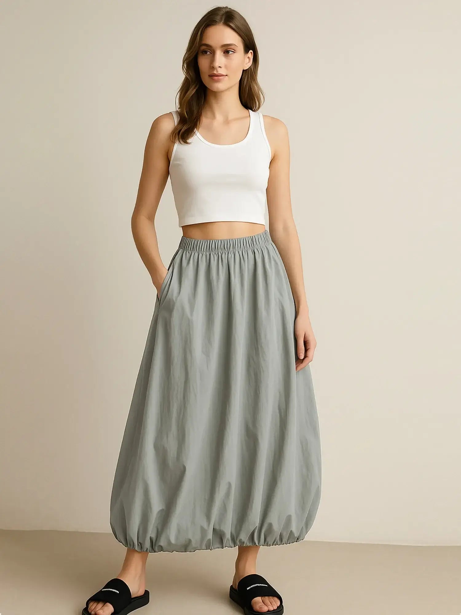 Model wearing a gray Elastic Waist Bubble Hem Maxi Skirt with paperbag waist and drawstring, styled with a white tank top.
