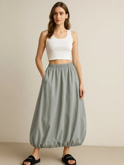 Model wearing a gray Elastic Waist Bubble Hem Maxi Skirt with paperbag waist and drawstring, styled with a white tank top.