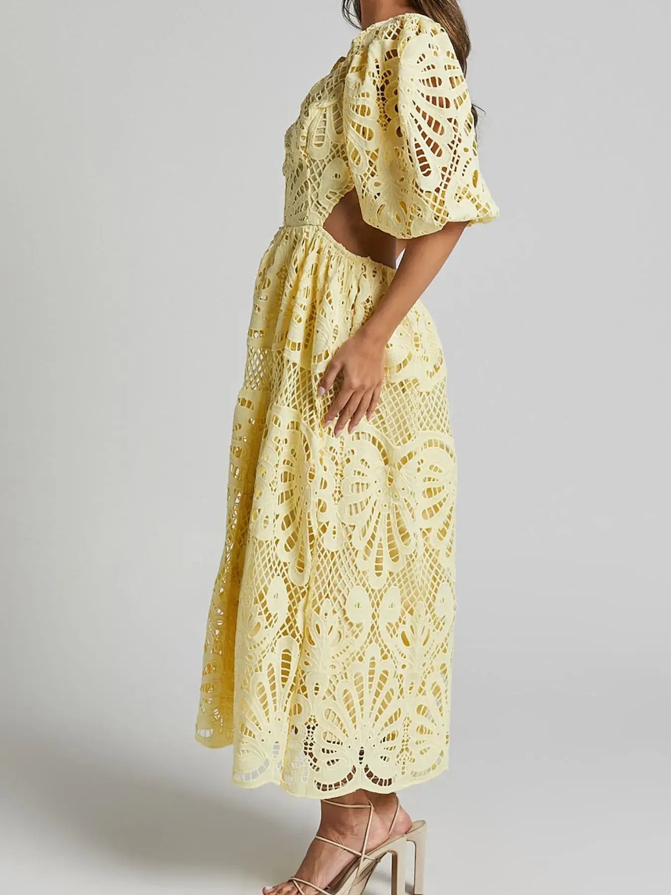 Woman wearing a yellow cutout back lace crochet V-neck dress with intricate detailing and puff sleeves, side view.