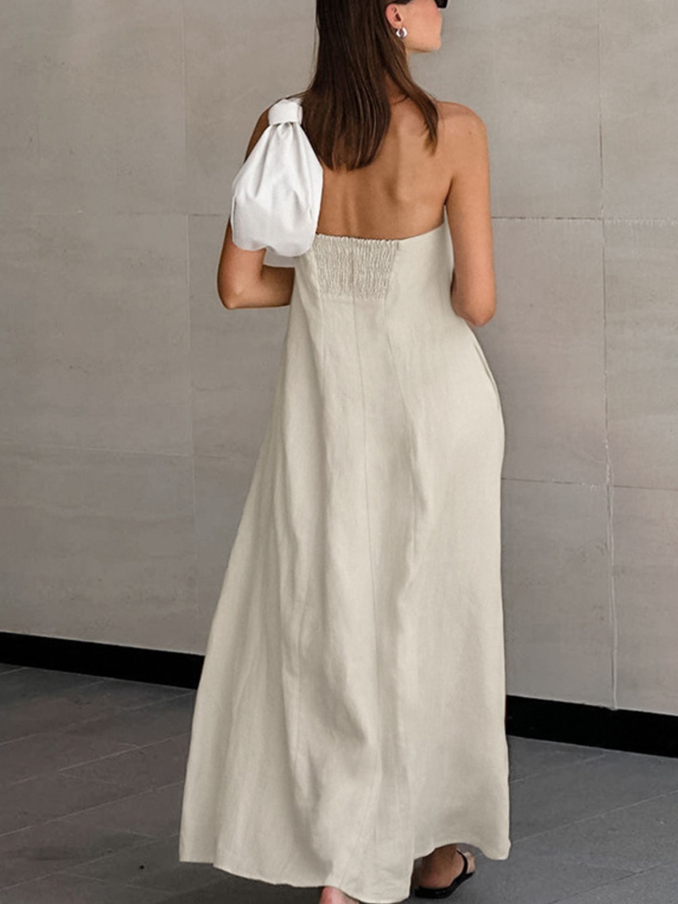 Back view of a woman wearing a Smocked Back Tube Dress with a relaxed silhouette and a white bag.