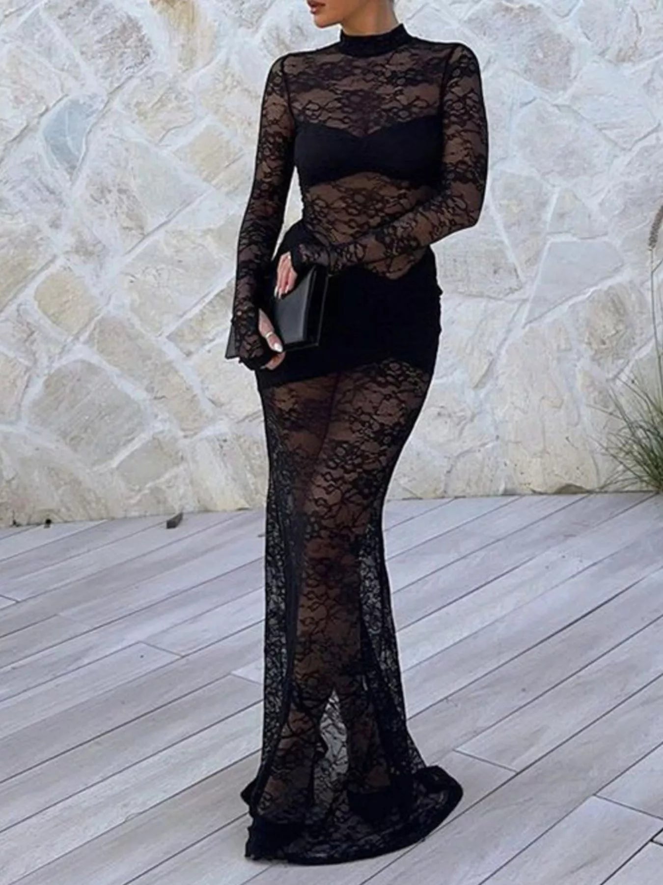 Woman wearing Lace Sheer Mock Neck Long Sleeve Maxi Dress against stone wall backdrop
