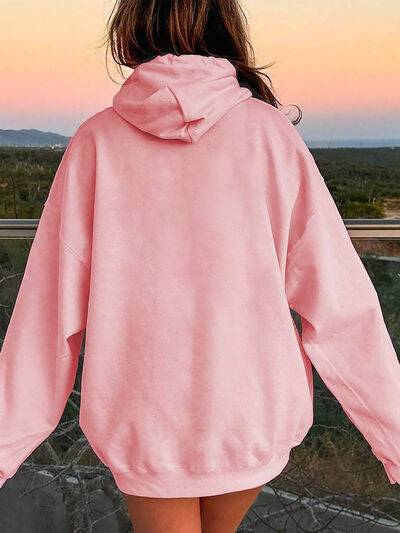 Back view of pink Drawstring Dropped Shoulder Hoodie styled in a sunset outdoor setting, showcasing relaxed streetwear fit.