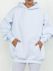 Woman wearing kangaroo pocket long sleeve hoodie in soft white, showcasing comfort and style with convenient pocket design.