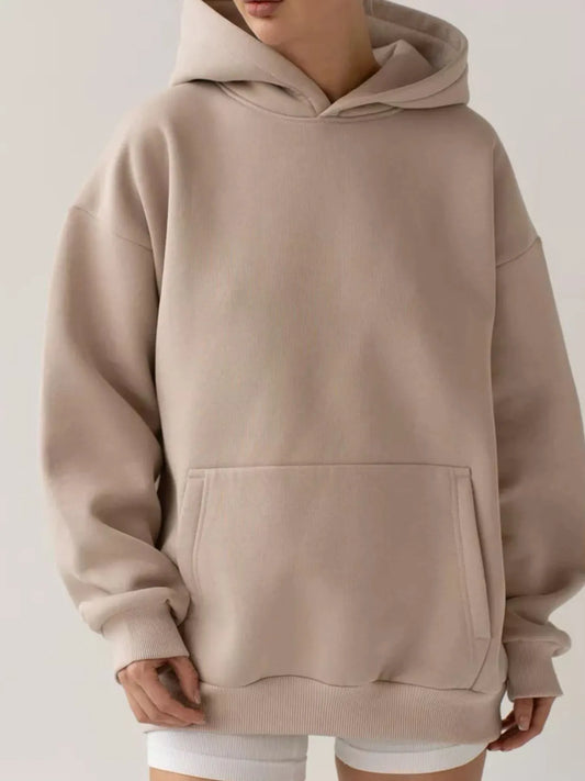 Woman wearing a beige kangaroo pocket long sleeve hoodie with a loose fit, showcasing its comfortable and stylish design.