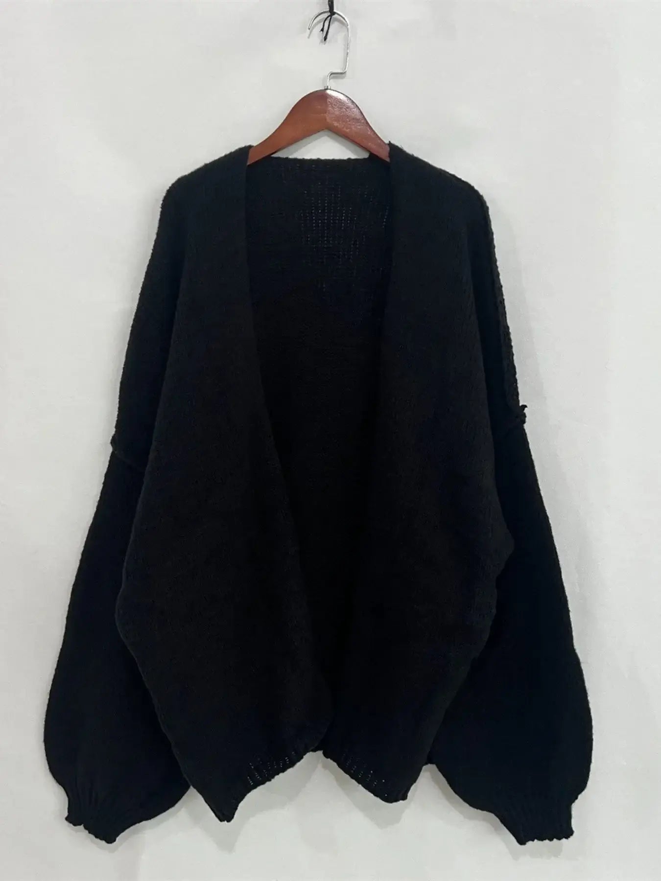 Black oversized open front dropped shoulder cardigan with voluminous sleeves, ideal for layering. Soft-touch polyester texture.