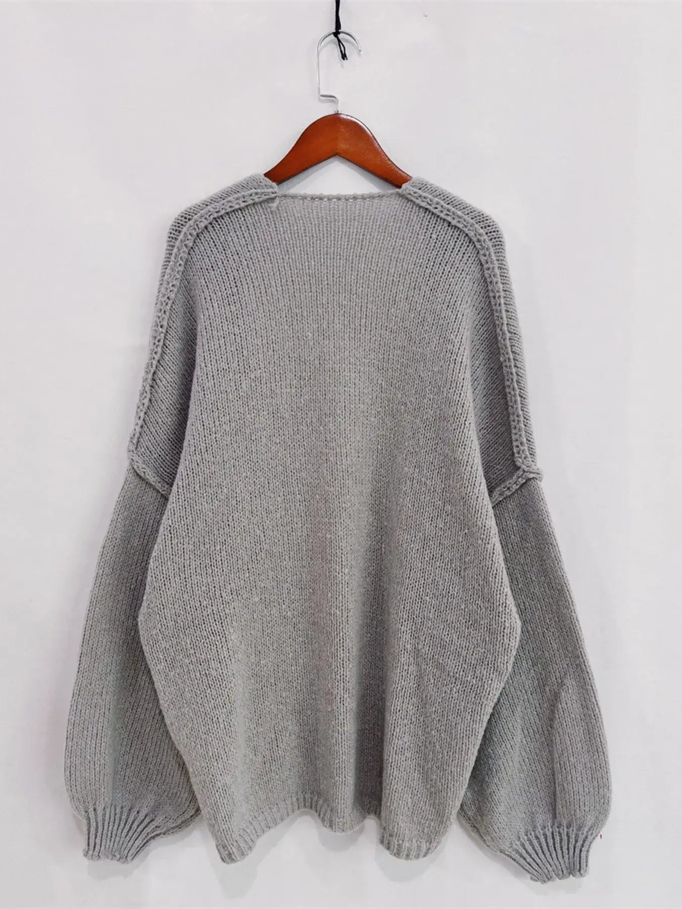 Gray open front dropped shoulder cardigan with oversized textured design on a wooden hanger.
