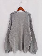 Gray open front dropped shoulder cardigan with oversized textured design on a wooden hanger.