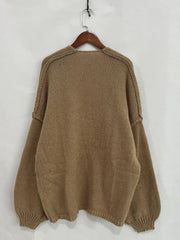 Back view of an oversized textured beige open front dropped shoulder cardigan with voluminous sleeves, hung on a wooden hanger.