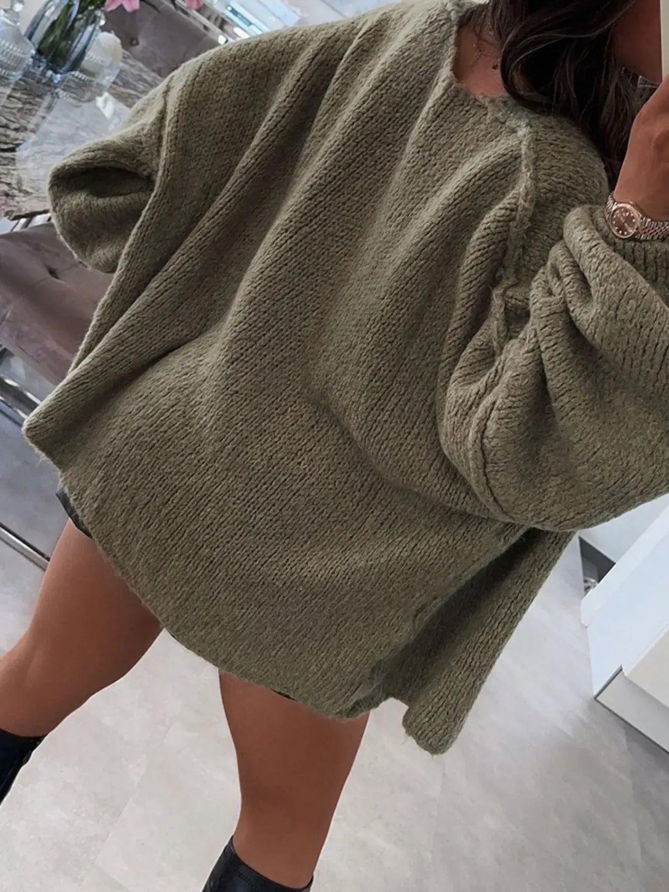 Woman wearing oversized, textured, olive green cardigan with dropped shoulders and voluminous sleeves, perfect for layering.