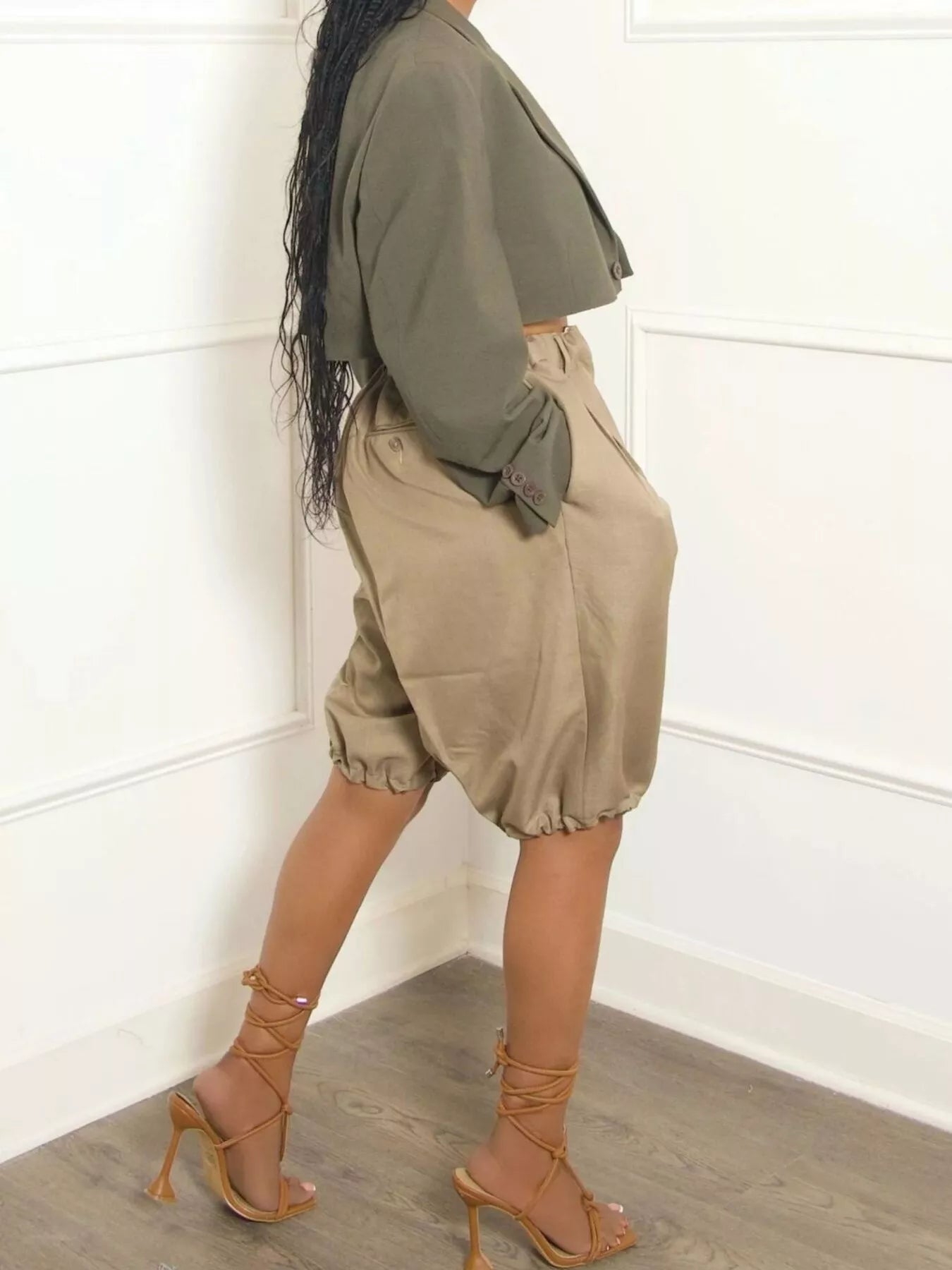 Model showcasing Pleated Detail High Waist Shorts with a cropped jacket and strappy heels, highlighting a chic outfit.