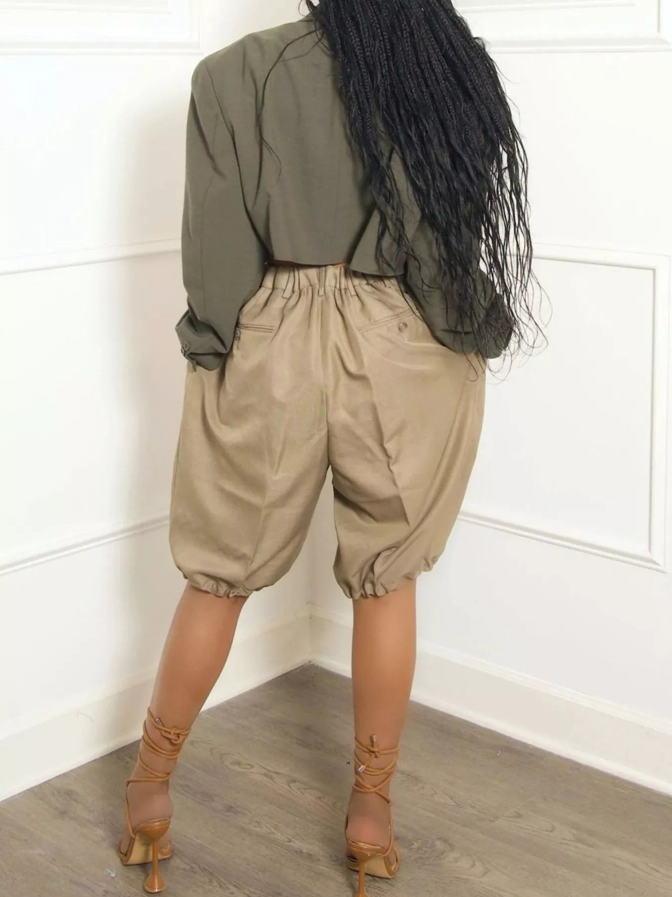 Woman wearing Pleated Detail High Waist Shorts with a relaxed fit and drawstring waist, styled with strappy heels.