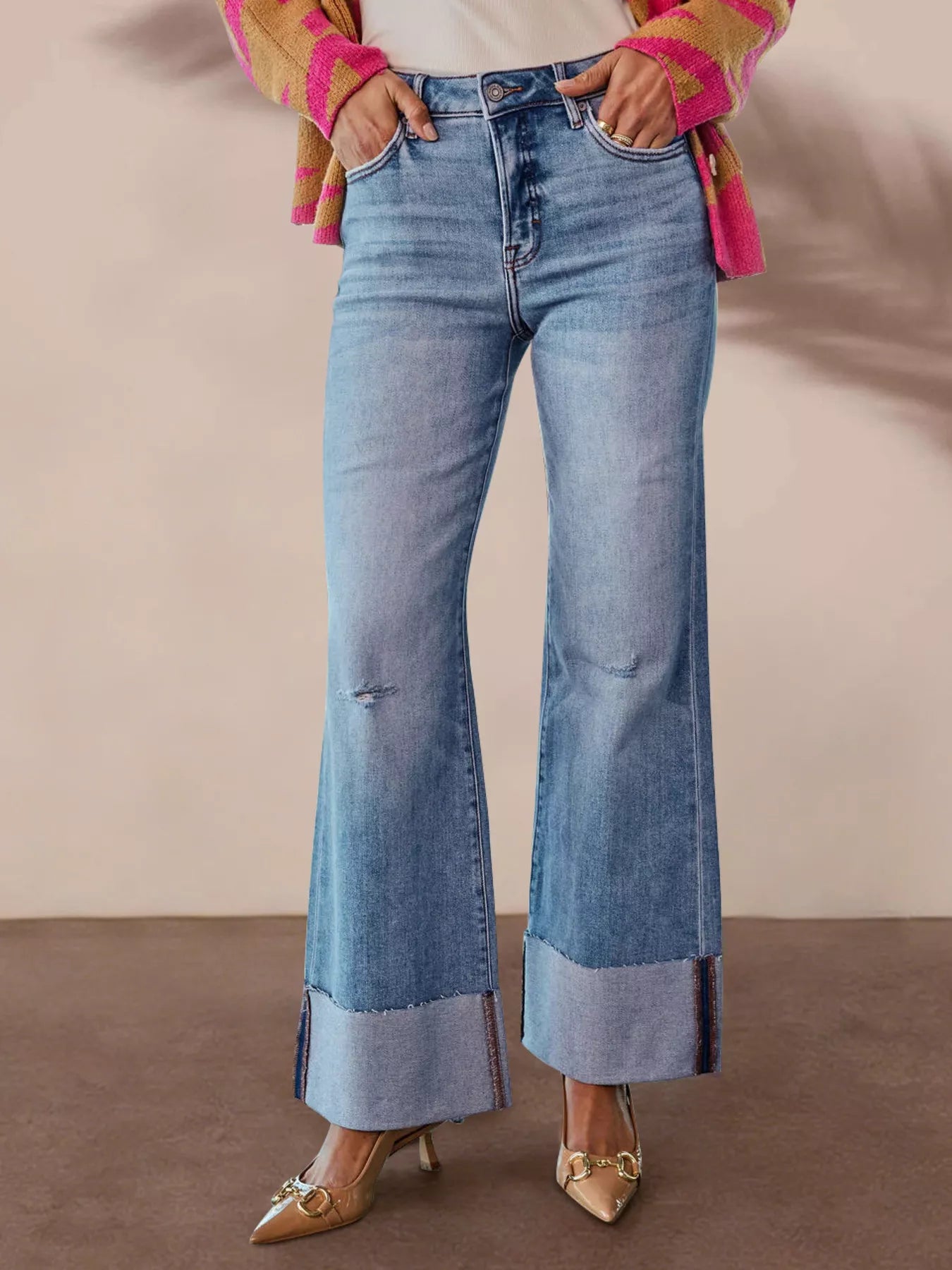 Distressed High-Waisted Flare Jeans worn with a colorful cardigan and stylish heels, highlighting the raw hem and slightly stretchy fit.
