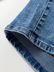 Close-up of seam detail on loose fit cropped jeans in blue denim fabric, showcasing modern stitching and relaxed design.