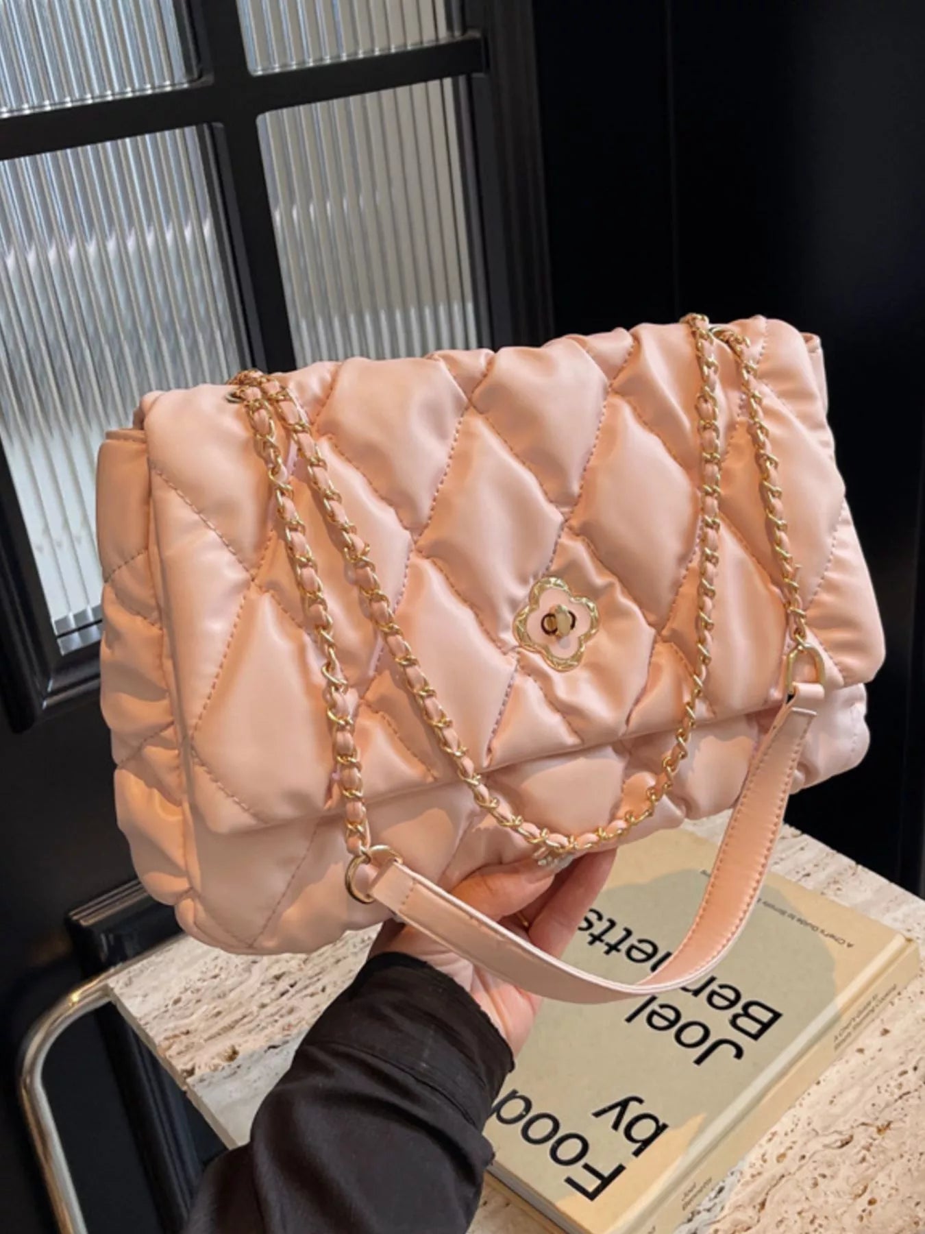 A person holding The Chicest Quilted Chain Shoulder Bag showcasing its plush design and elegant chain straps.