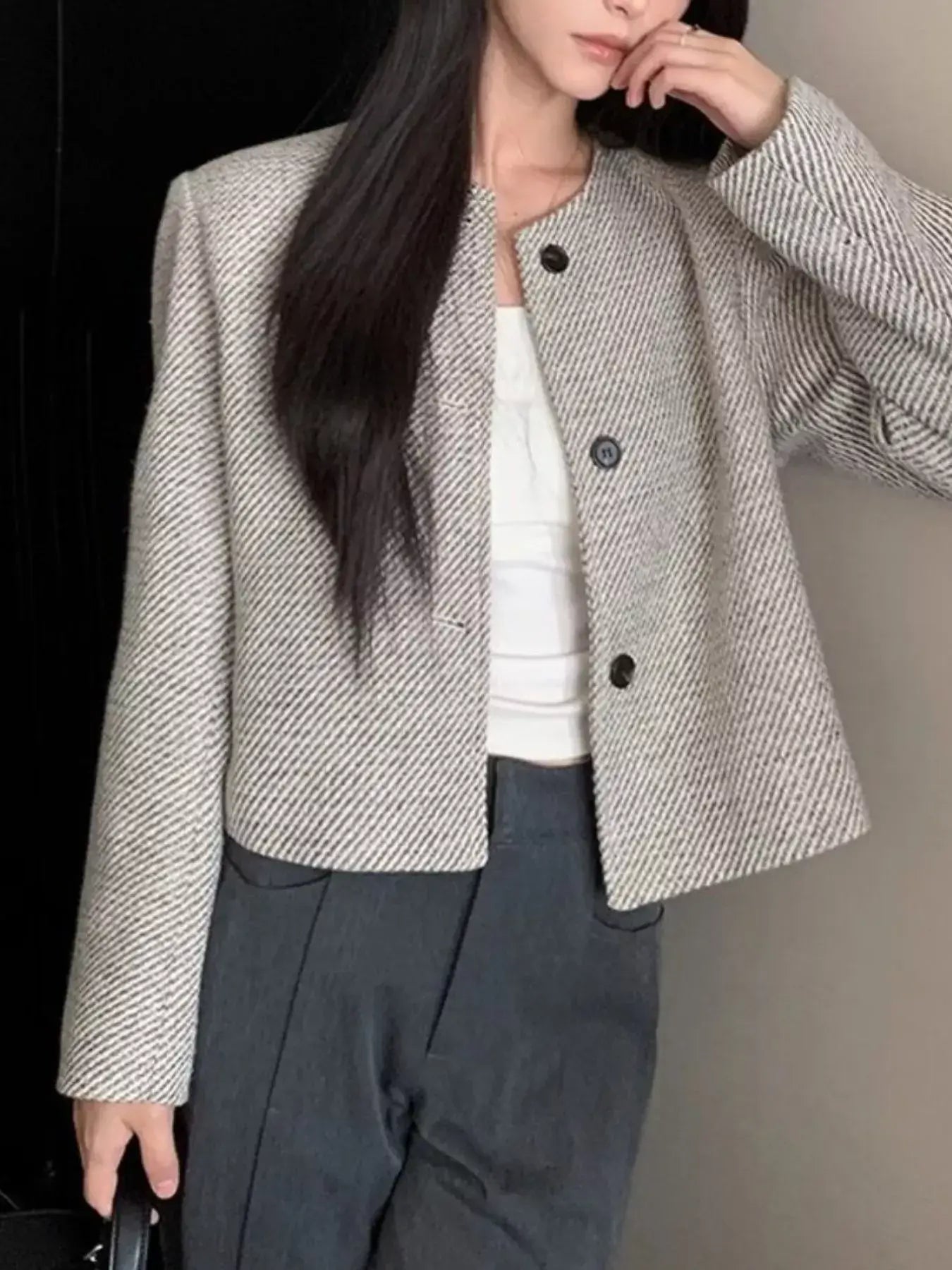 Woman wearing a Tweed Cropped Jacket with buttoned front, made from 100% polyester, styled with dark pants and a white top.